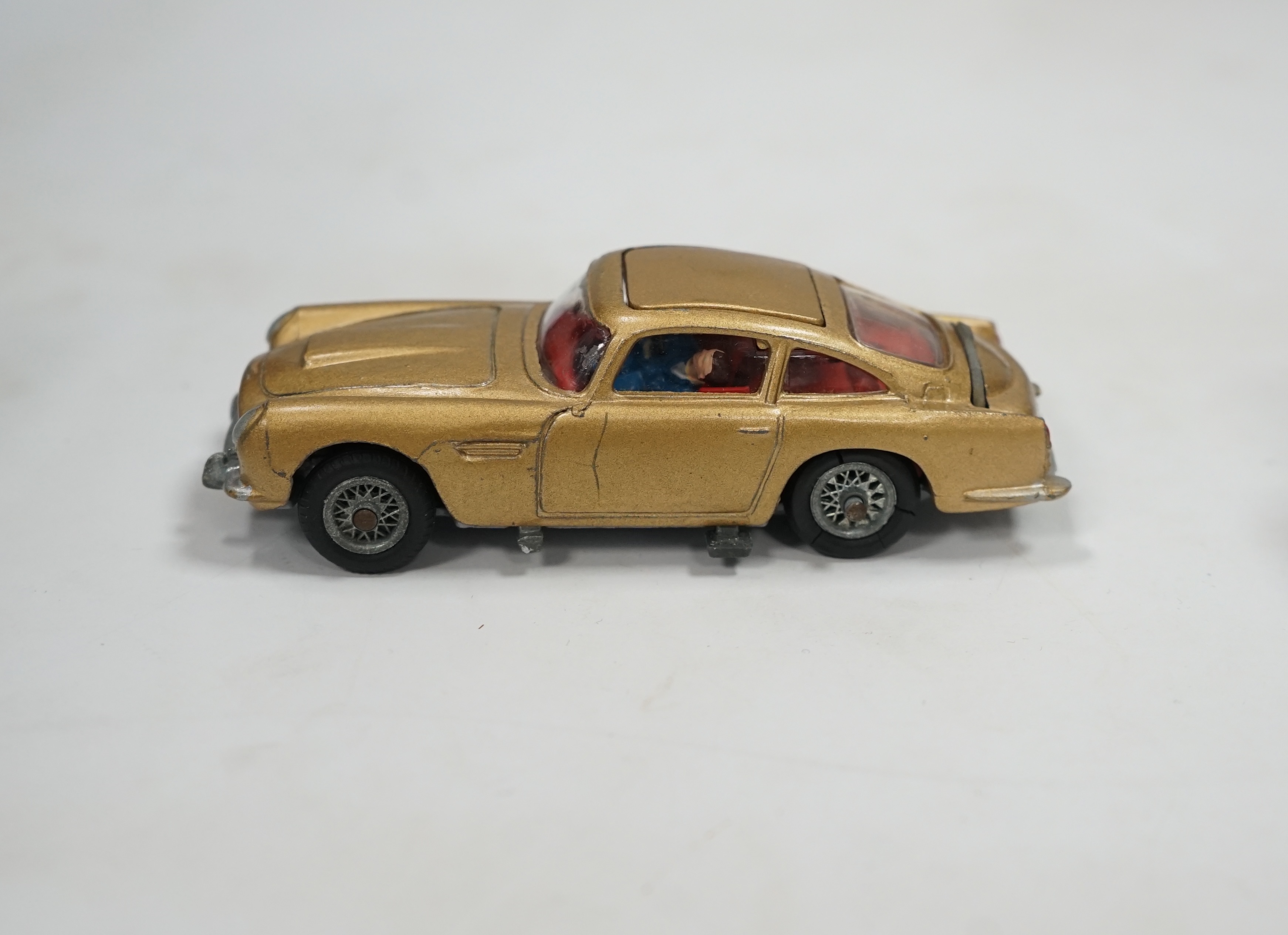 A Corgi Toys (261) James Bond 007 Aston Martin in gold, together with its original box, card display stand, secret instructions and envelope, and an additional spare passenger. Condition fair to good, minor chips to the